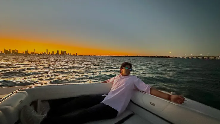 A person relaxing on a boat at sunset with a city skyline beyond